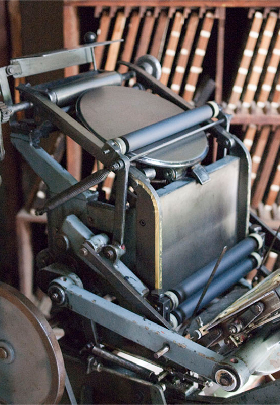 （写真12）半自動の印刷機。紙を手動でセットし、プレスの動作が自動で行える。こちらの機械では、金属活字で組んだ版を印刷する場合に利用しているとのこと。